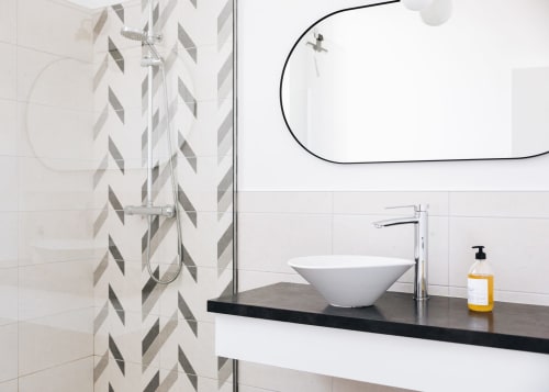 Salle de bains moderne à La Maison D'olivier avec douche aux carreaux géométriques, vasque blanche et meuble noir à Mesnard la