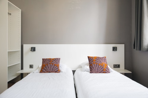 Deux lits jumeaux aux oreillers à motifs orange dans la chambre moderne de La Maison D'olivier, Mesnard la Barotière