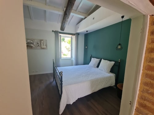 Camera luminosa presso la Chambre d'hôtes Gîte Le Tilleul con letto queen, parete color turchese e travi a vista a Le Martinet