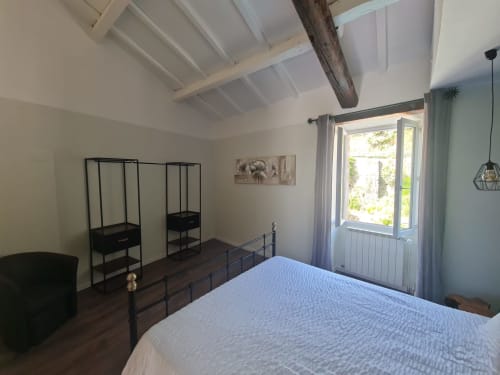 Camera spaziosa con letto in ferro, travi a vista e terrazza con vista sulla piscina presso la Chambre d'hôtes Gîte Le Tilleul