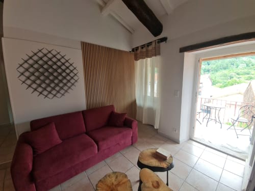 Soggiorno cottage moderno con divano bordeaux, tavolini in legno e porta-finestra con vista sulla piscina presso Le Tilleul