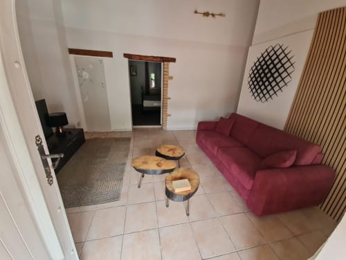 Salotto privato con divano bordeaux, tavolini in legno e arte moderna alle pareti presso Chambre d'hôtes Gîte Le Tilleul, Le Martinet