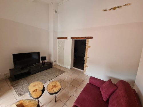 Salotto privato presso Chambre d'hôtes Gîte Le Tilleul con divano bordeaux, TV a schermo piatto e tavolini in legno