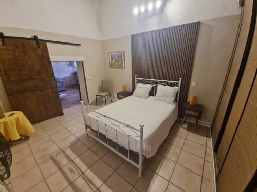 Camera luminosa di Chambre d'hôtes Gîte Le Tilleul con letto in metallo, biancheria color crema, tende scure e pavimento piastrellato