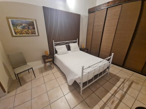 Camera da letto con letto in metallo bianco, armadio in legno, comodino e sedia presso Chambre d'hôtes Gîte Le Tilleul