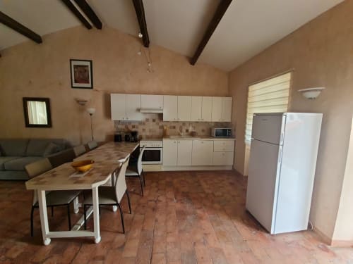 Cucina aperta e sala da pranzo presso Gîte Le Tilleul, Le Martinet, con mobili bianchi, pavimento in cotto e zona soggiorno
