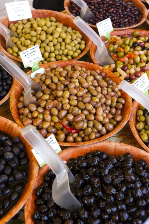 Assorted olives and pickled vegetables at L'Amiradou market display in Félines-sur-Rimandoule, France