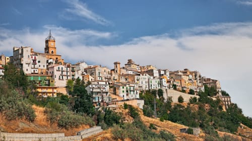 Il pittoresco borgo collinare di Atessa, Italia, con edifici colorati e torre dell'orologio che dominano il paesaggio ondulato