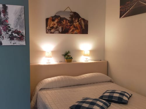 Cozy bedroom at Casa Meravigliosa with bed, bedside lamps, religious artwork, and plants in Fontanafredda