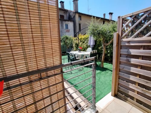 Private garden patio at Casa Meravigliosa with wooden privacy screens, seating area, and lush greenery in Fontanafredda