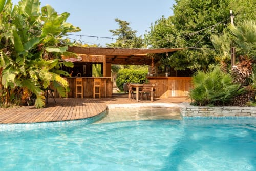 Poolhouse et piscine turquoise entourée de palmiers et transats – maison avec piscine privée à Hyères, Var.
