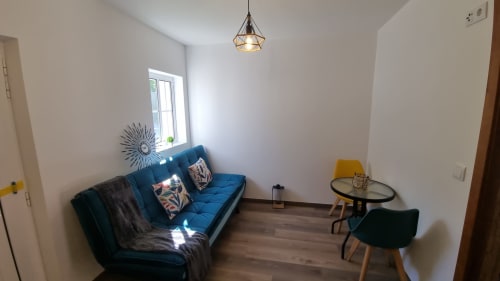 Sala de estar moderna com sofá azul, mesa redonda e luminária pendente no apartamento Casa da Oliveirinha, Leiria