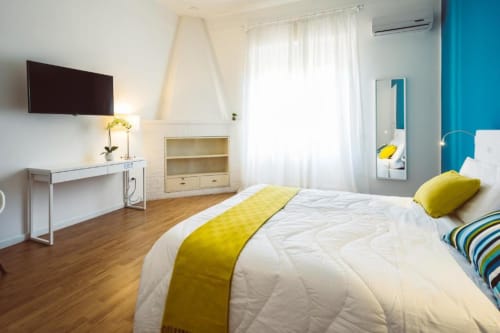 Camera luminosa al Bluemoon Sardinia B&B di Cagliari con letto bianco, dettagli gialli, TV e servizi moderni