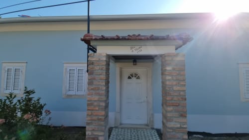 Entrada do apartamento Casa da Oliveirinha de paredes azuis em Leiria, com pórtico de tijolos e porta branca