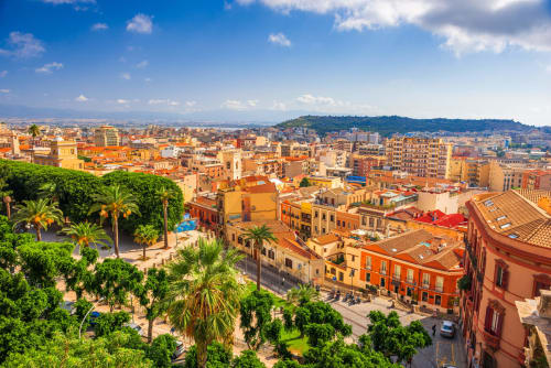Paesaggio urbano colorato di Cagliari con edifici in terracotta, palme e architettura mediterranea presso Bluemoon Sardegna