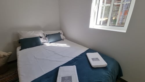 Modern bedroom at Charm Discovery Experiences in Leiria with garden view, white bedding, navy accents, and skylight window