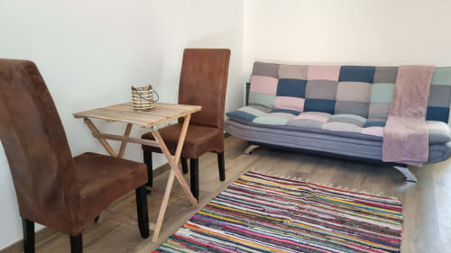 Coin salon cosy à Casa do Lume à Leiria avec tapis rayé coloré, chaises marron, table en bois et patchwork