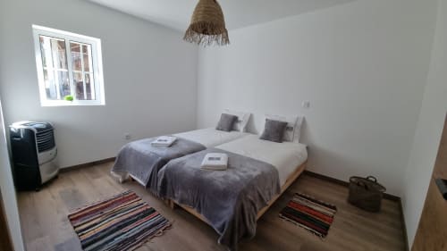 Deux lits jumeaux dans l'appartement Casa do Lume de Charm Discovery Experiences, Leiria, avec luminaire suspendu tressé et tapis rayés