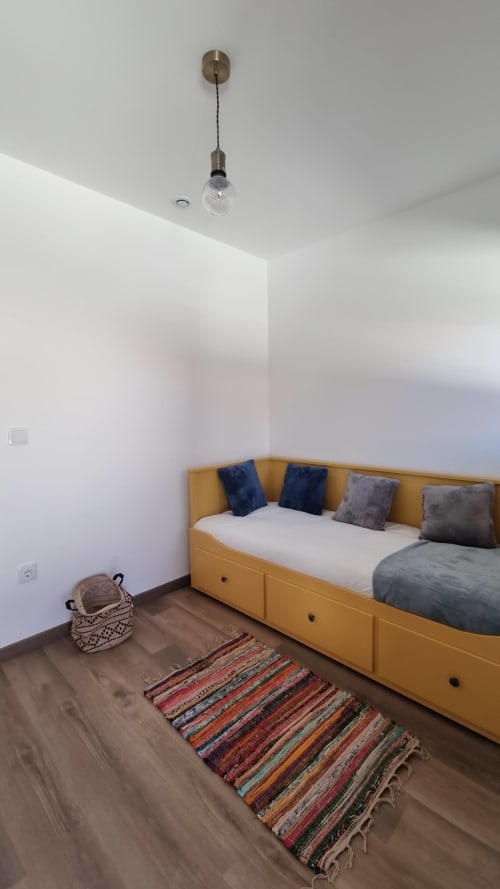 Chambre moderne avec lit jaune, tapis coloré et suspension à Casa do Lume, Leiria