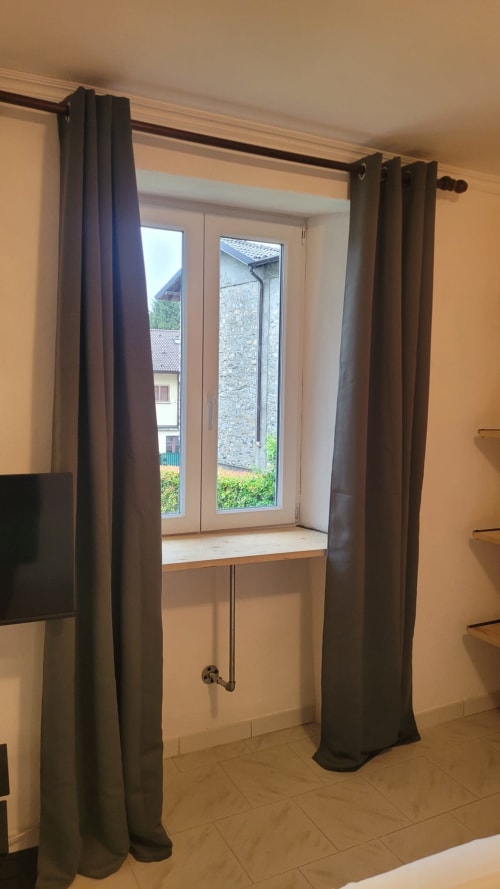 Moderno appartamento con tende scure che incorniciano porte-finestre con vista sulle montagne nella THE V Collection di Milano