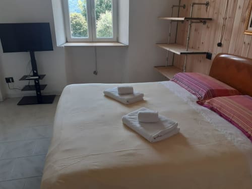 Ampia camera da letto nell'Apartment Sormano 3 di THE V Collection Milano con vista montagna, letto bianco e servizi moderni