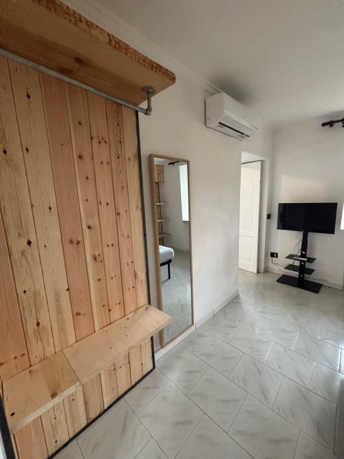 Soggiorno moderno con porte scorrevoli in legno, TV su supporto, pareti bianche e pavimento in piastrelle presso THE V Collection