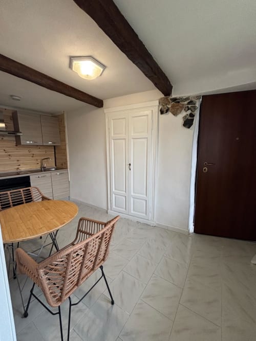 Zona cucina-living moderna nell'Apartment Sormano 3 di THE V Collection Milano con tavolo in legno, sedie intrecciate e guardaroba bianco