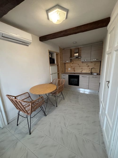 Moderna zona cucina-pranzo nell'Appartamento Sormano 3 della THE V Collection Milano con tavolo in legno, sedie in rattan e completo di attrezzature