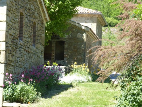 Stone courtyard at L'Amiradou B&B in Félines-sur-Rimandoule with flowering garden and medieval architecture