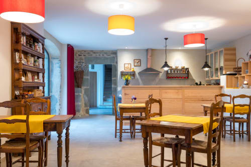 Salle à manger de L'Amiradou BnB à Félines-sur-Rimandolle avec chaises en bois, coussins jaunes et suspensions colorées