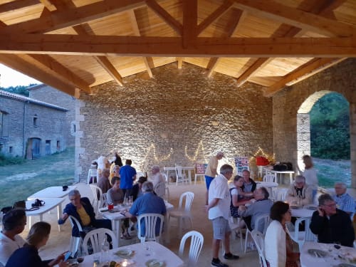 Guests dining under wooden beams at L'Amiradou, a rustic stone venue in Félines-sur-Rimandoule