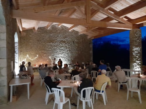 Evening dining event at L'Amiradou B&B in Félines-sur-Rimandoule with guests at white tables under wooden beams