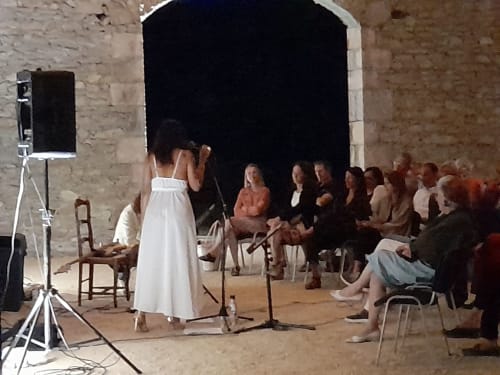 Intimate performance event at L'Amiradou B&B in Félines-sur-Rimandoule, with audience seated around performer in stone room