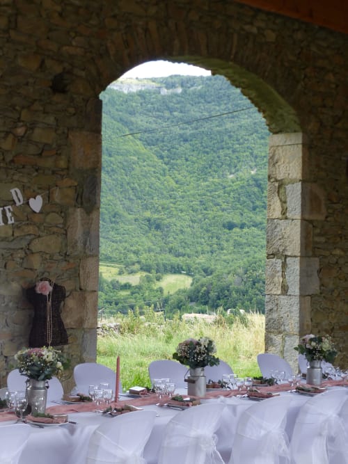 Elegant dining setup at L'Amiradou with stone archway framing lush Félines-sur-Rimandoule valley views