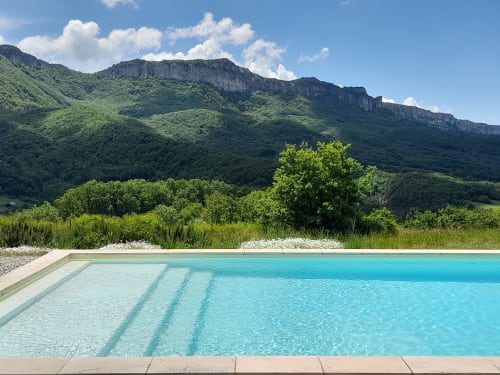 Turquoise pool overlooking green mountains at L'Amiradou B&B, Félines-sur-Rimandoule, France