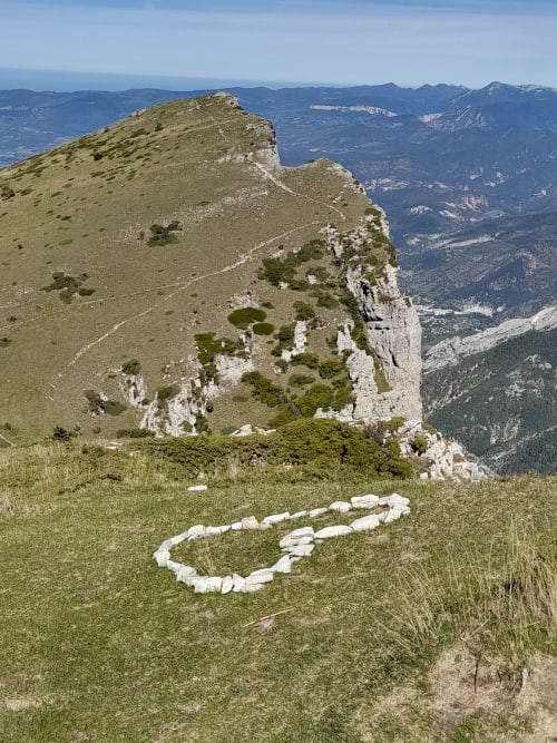 Alpine meadow with white stone heart marker overlooking Félines-sur-Rimandoule valley, L'Amiradou BnB location
