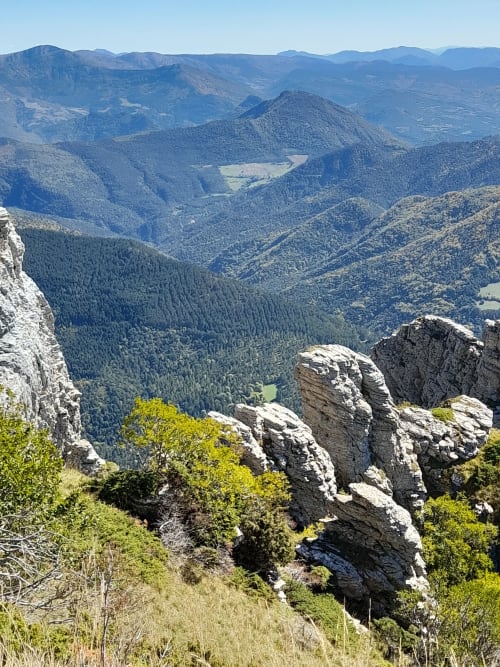 Rocky cliffs overlook forested valleys and mountains near L'Amiradou B&B in Félines-sur-Rimandoule, France