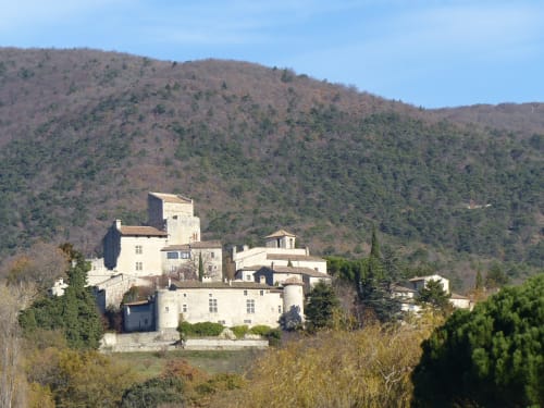 L'Amiradou stone mansion perched on hillside in Félines-sur-Rimandoule, France surrounded by forested mountains