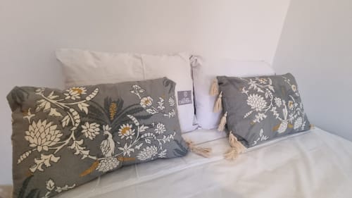 Decorative throw pillows with floral embroidery and tassels arranged on white bedding at Charm Discovery Experiences villa in