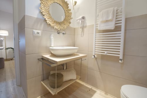 Bagno moderno all'hotel Cuore di Rocca a Rocca di Papa con lavabo d'appoggio, scaldasalviette e specchio dorato a raggiera