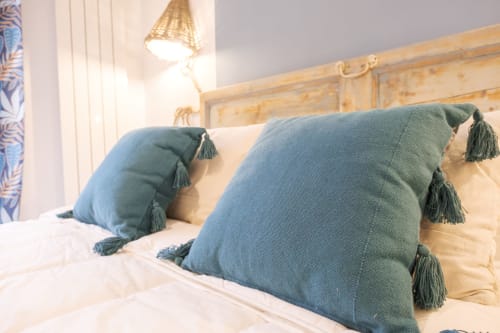 Camera accogliente all'hotel Cuore di Rocca a Rocca di Papa con cuscini turchesi guarniti di nappine su letto in legno