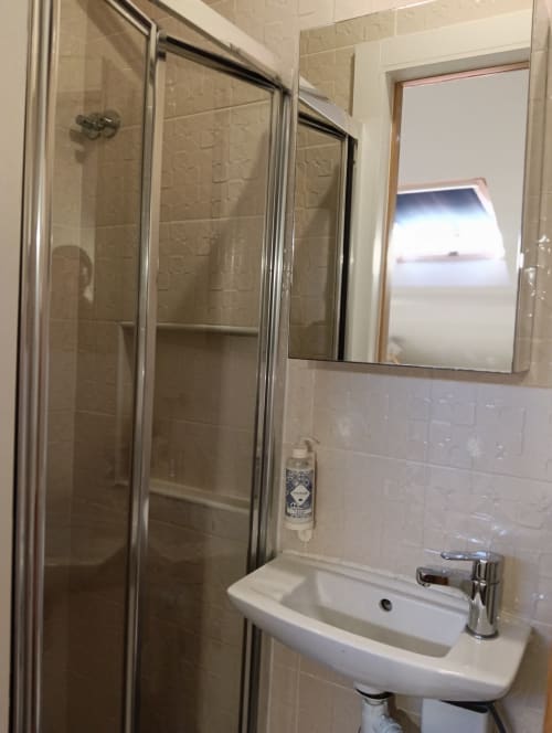Modern bathroom with shower enclosure, white sink, and mirror at Vila Alexandra hostel, Costa da Caparica