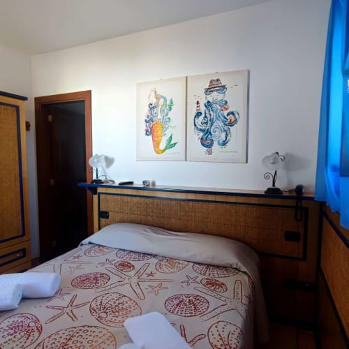 Accogliente camera matrimoniale all'Hotel Principe di Rinella con decorazioni a tema nautico, arredi in legno e ispirazioni marine