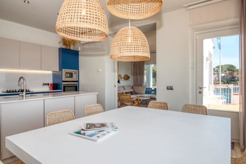 Modern kitchen and dining area at Finques Garcia Enrich in Palafrugell with woven pendant lights and coastal views