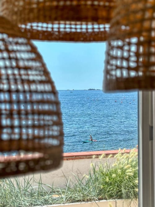 Coastal view through brick archway at Finques Garcia Enrich hotel in Palafrugell, with beach, sea, and swimmer visible