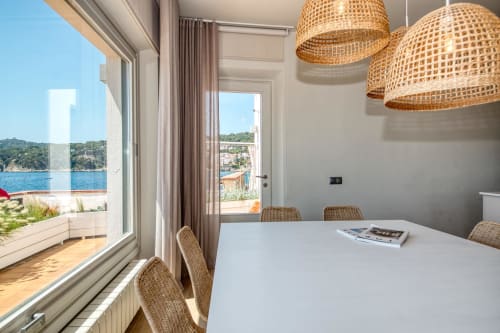 Modern dining area at Finques Garcia Enrich in Palafrugell with coastal sea views, woven pendant lights, and wicker chairs