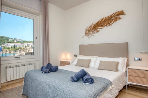 Bright modern bedroom at Finques Garcia Enrich in Palafrugell with coastal views, beige upholstered bed, and Mediterranean