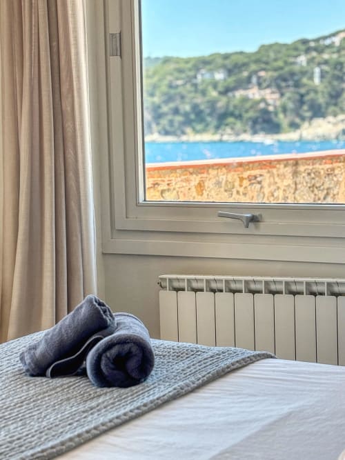 Bedroom window view at Finques Garcia Enrich hotel in Palafrugell with folded towels, coastal cliffs, and blue sea