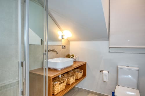Modern bathroom at Finques Garcia Enrich hotel in Palafrugell with vessel sink, wooden vanity, and storage baskets