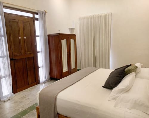 Habitación luminosa en Casa Tuch BnB de Mérida con ropa de cama blanca, armario de madera y puertas tradicionales